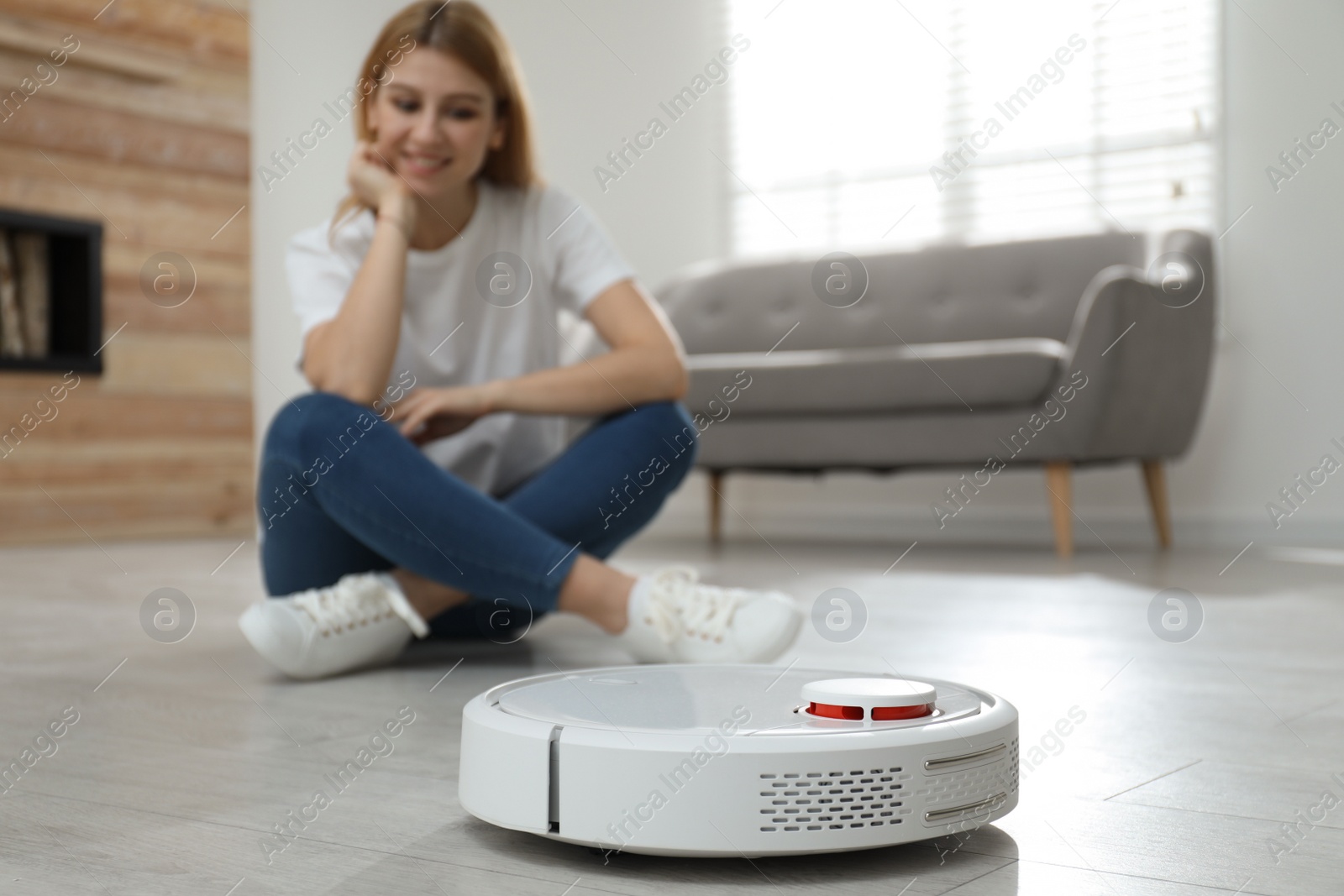 Photo of Woman using robotic vacuum cleaner at home