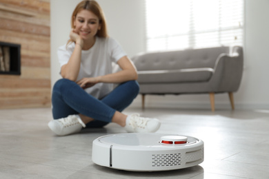 Photo of Woman using robotic vacuum cleaner at home