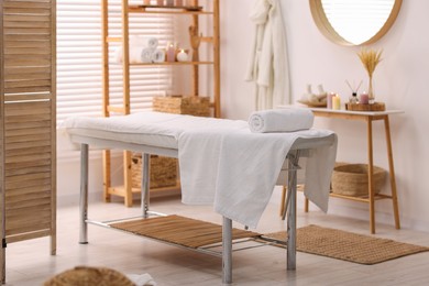 Comfortable massage table with clean towels in spa center