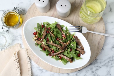 Photo of Delicious salad with beef tongue, arugula, seeds and fork served on white marble table, flat lay