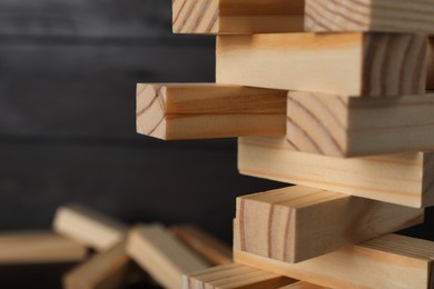 Photo of Jenga tower made of wooden blocks on blurred background, closeup