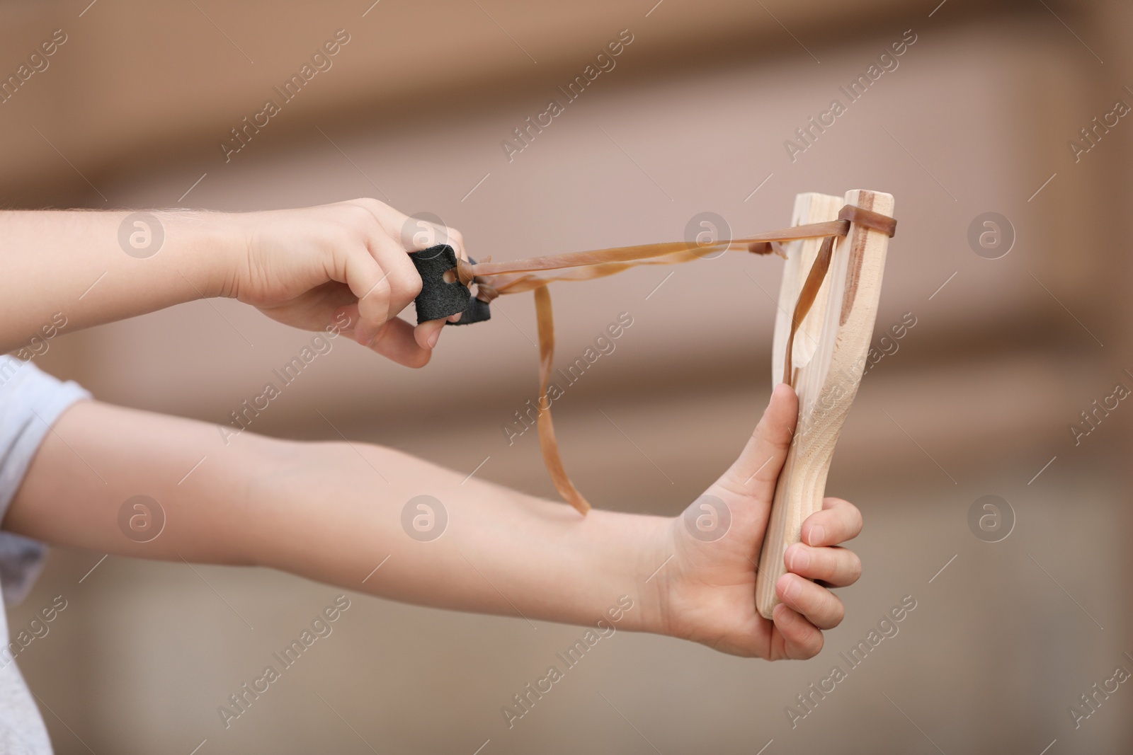 Photo of Little girl playing with slingshot outdoors, closeup