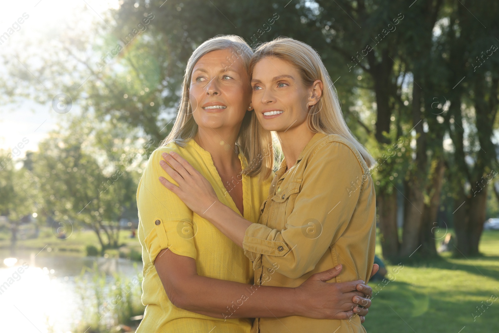 Photo of Family portrait of mother and daughter hugging in park on sunny day