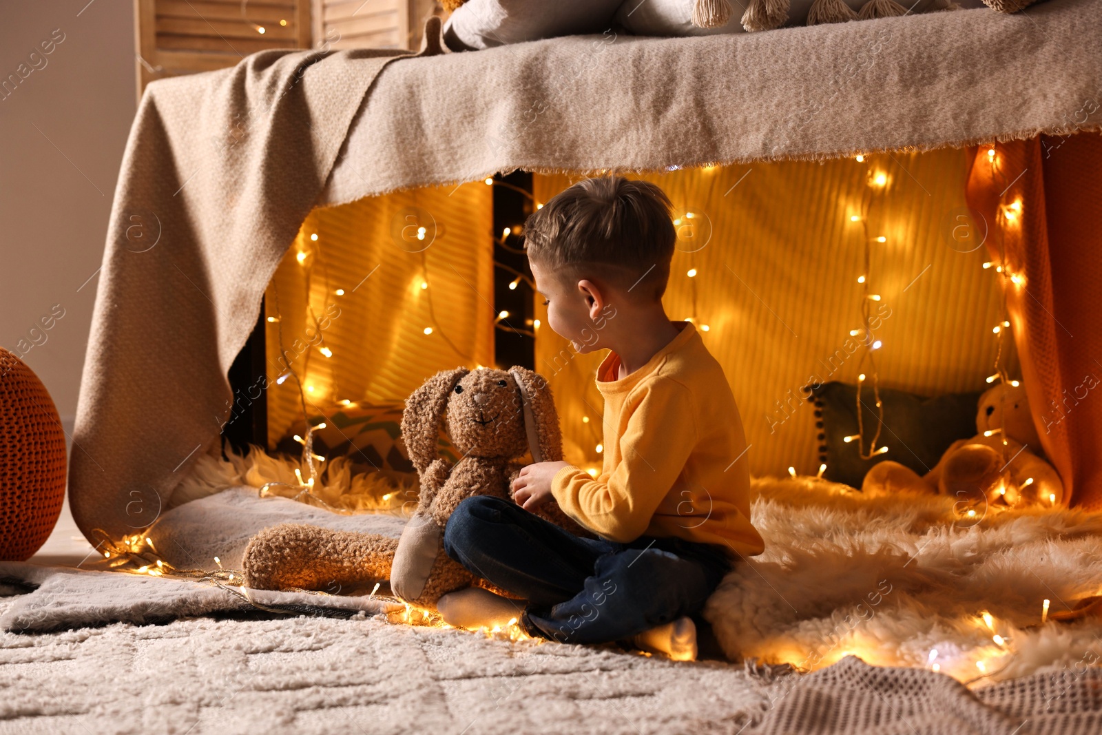 Photo of Boy playing with toy bunny in play tent at home