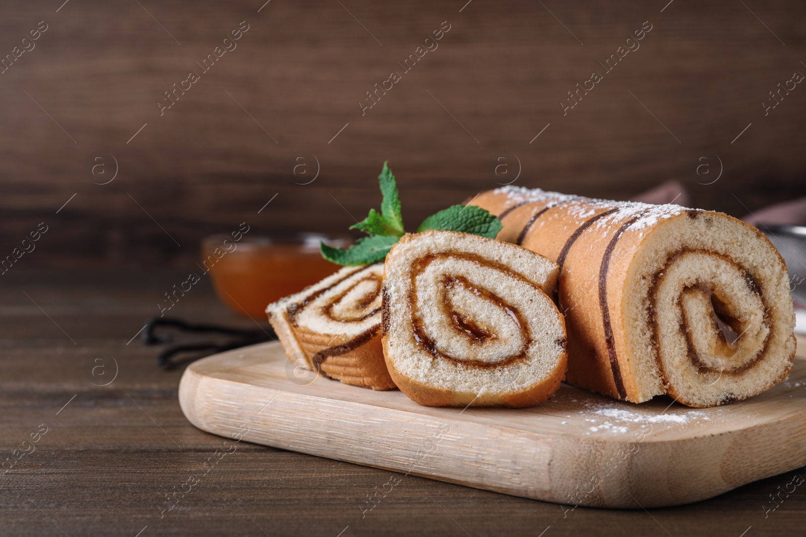 Photo of Tasty cake roll with jam on wooden table, space for text