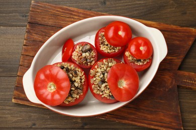 Photo of Delicious stuffed tomatoes with minced beef, bulgur and mushrooms on wooden table, top view