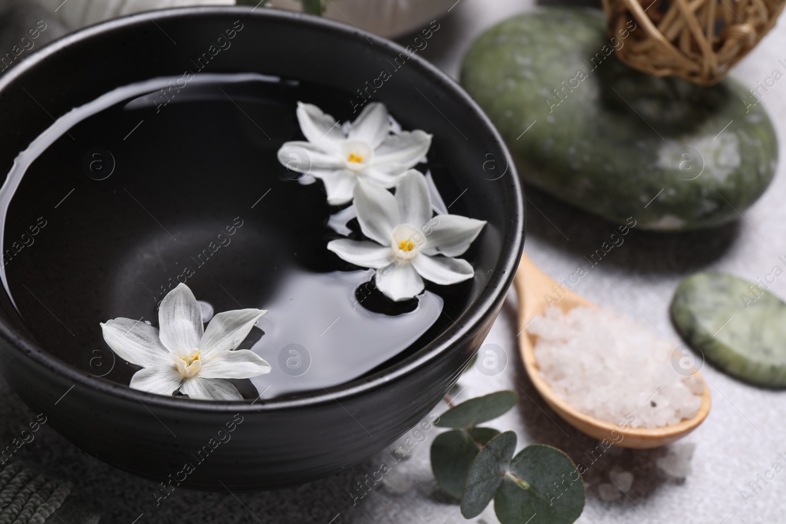 Photo of Beautiful composition with spa products and flowers on light grey table, closeup