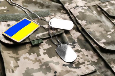 Image of Ukrainian army flag patch and military ID tags on camouflage uniform