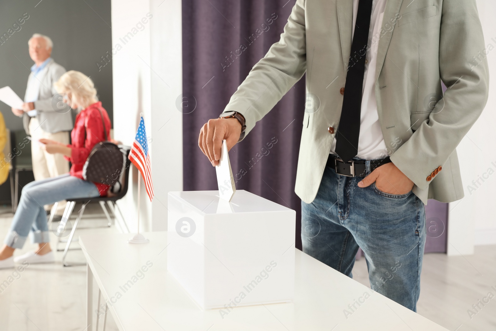 Photo of Man putting ballot paper into box at polling station