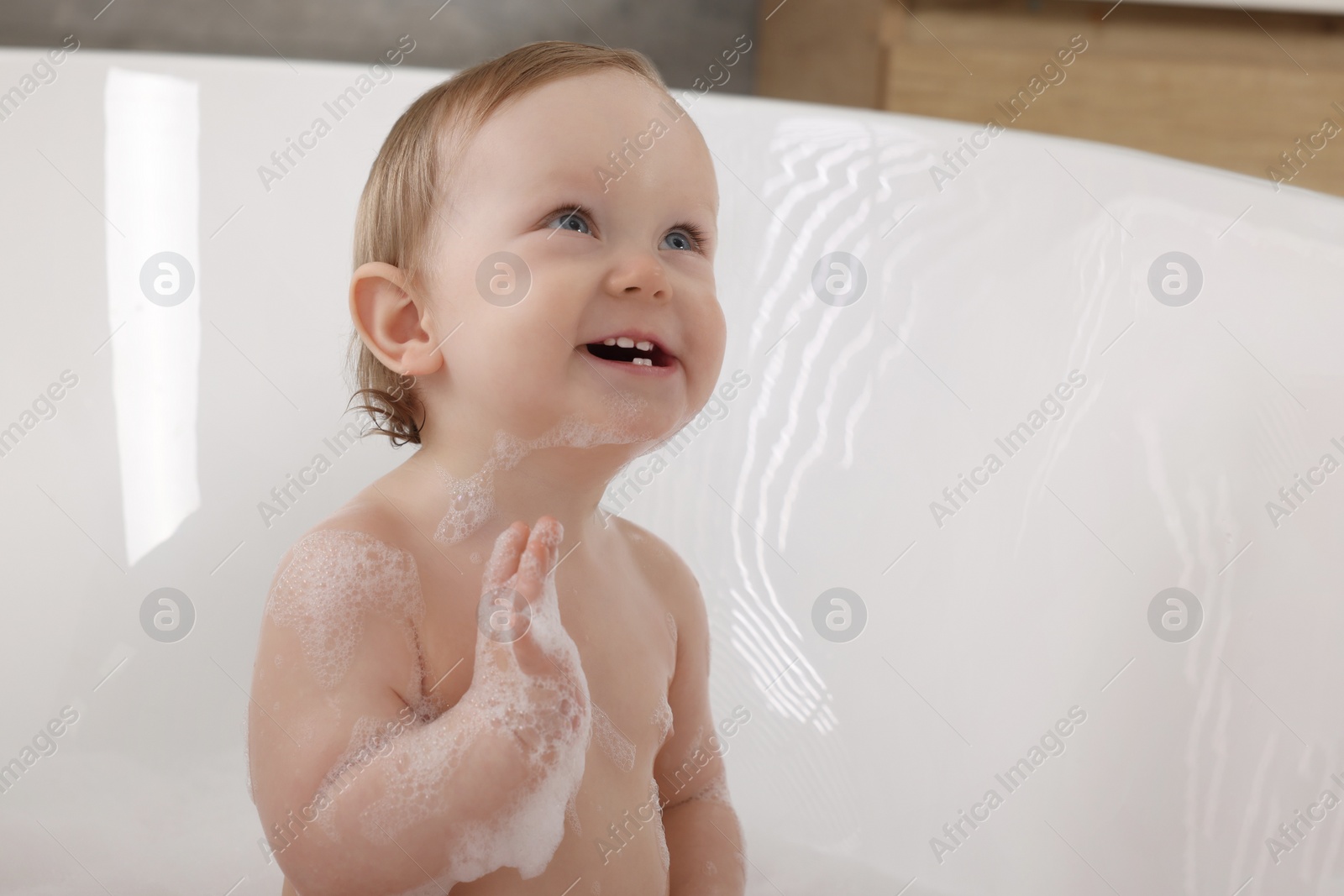 Photo of Mother washing her little baby in tub at home, closeup