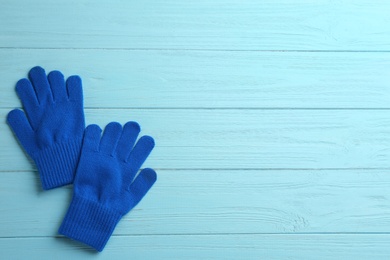 Pair of stylish woolen gloves on light blue wooden background, flat lay. Space for text