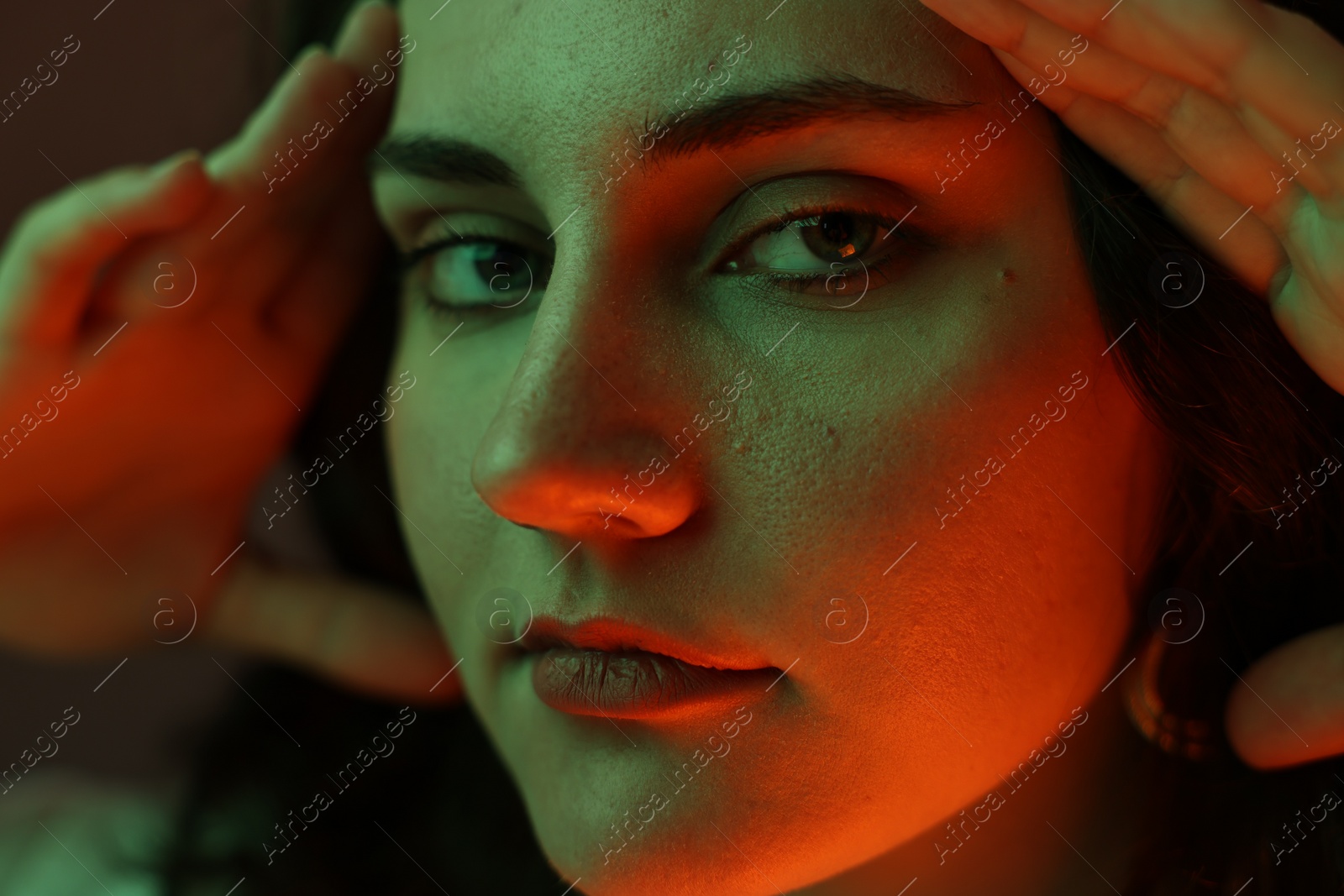 Photo of Portrait of beautiful young woman on color background with neon lights, closeup