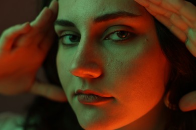 Portrait of beautiful young woman on color background with neon lights, closeup