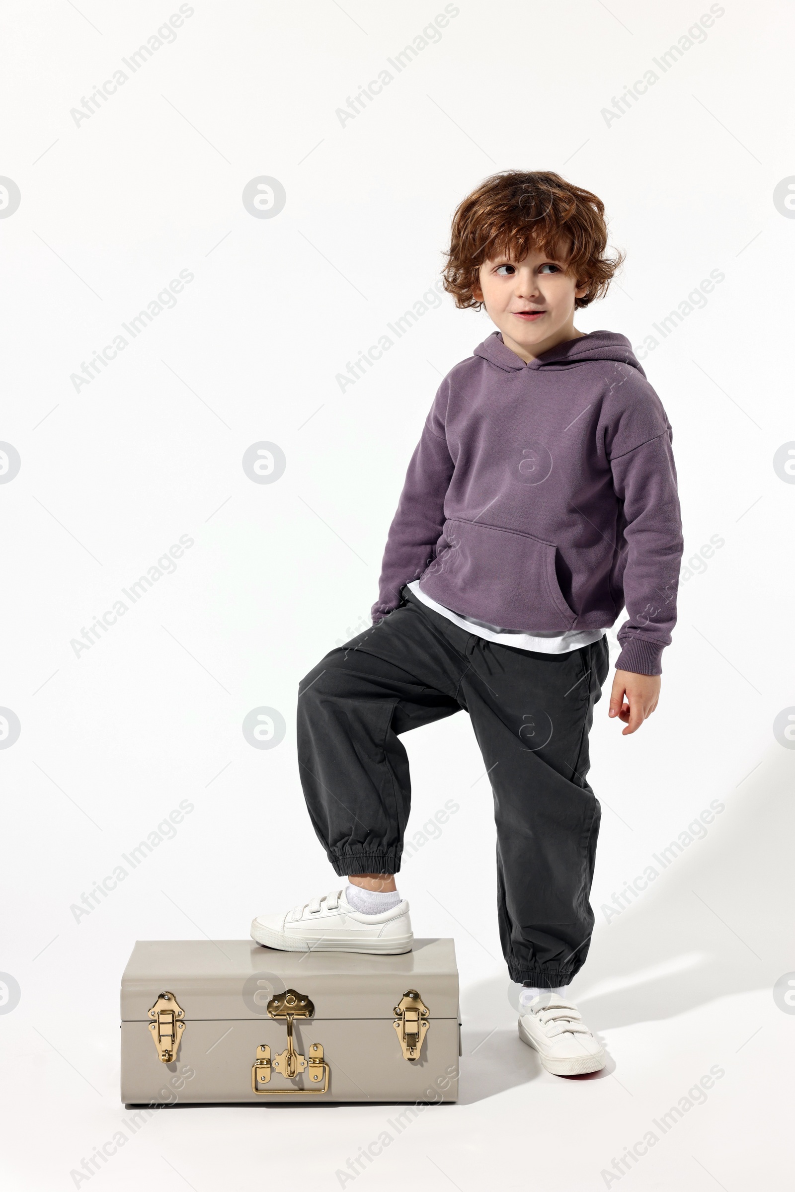 Photo of Fashion concept. Stylish boy with vintage suitcase on white background