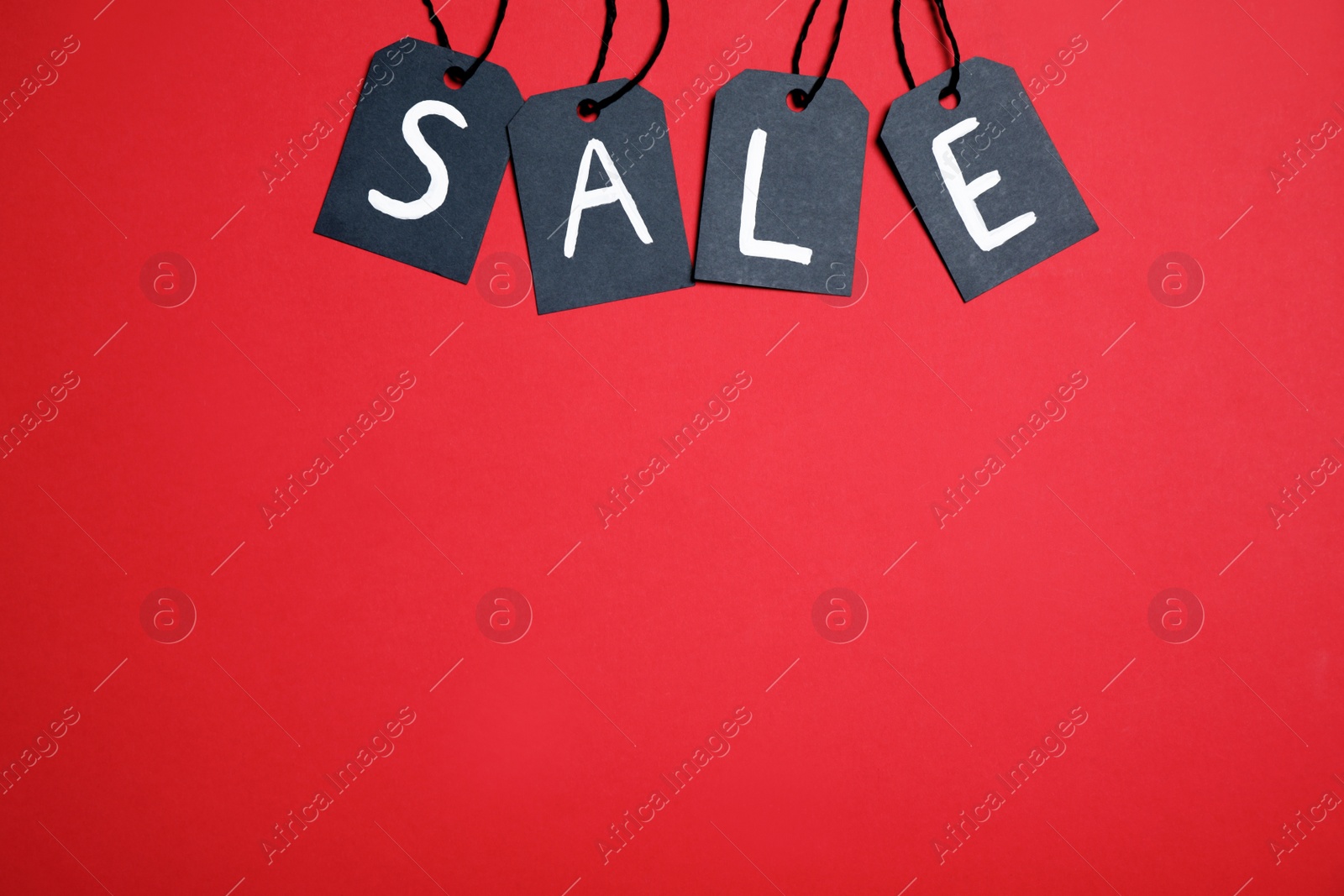 Photo of Word SALE made with black tags on red background, flat lay. Space for text