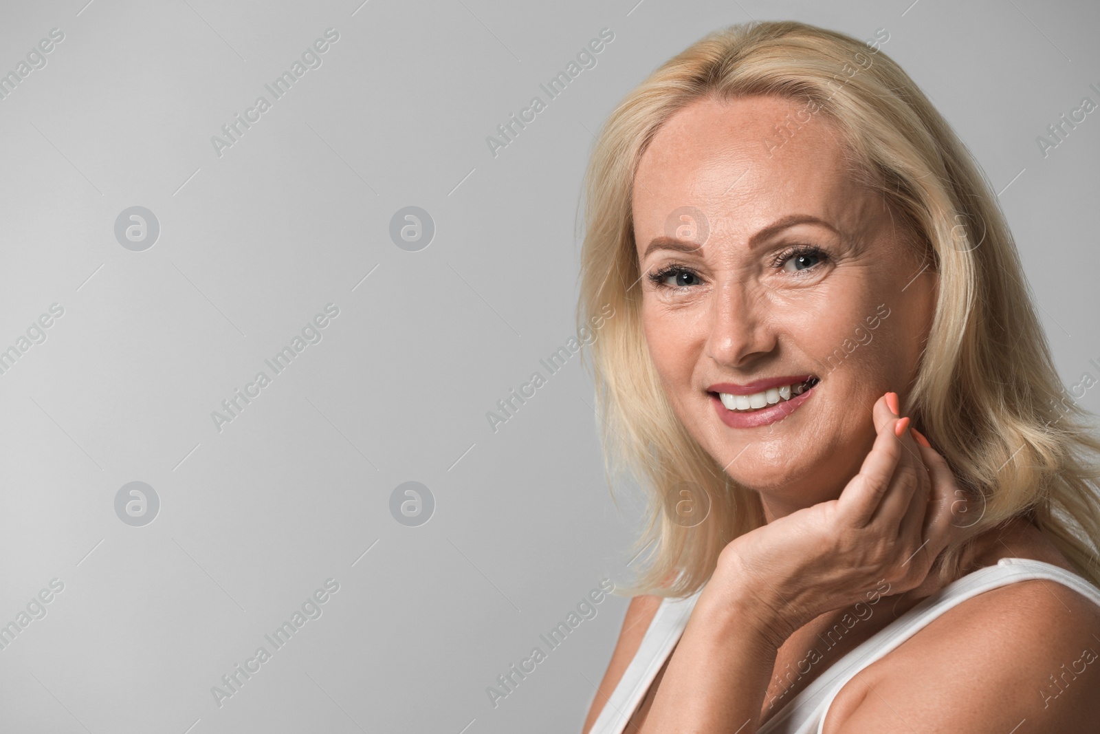 Photo of Portrait of beautiful mature woman with perfect skin on grey background. Space for text