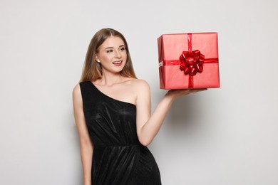 Photo of Portraitbeautiful young woman in elegant black dress with red gift box on white background