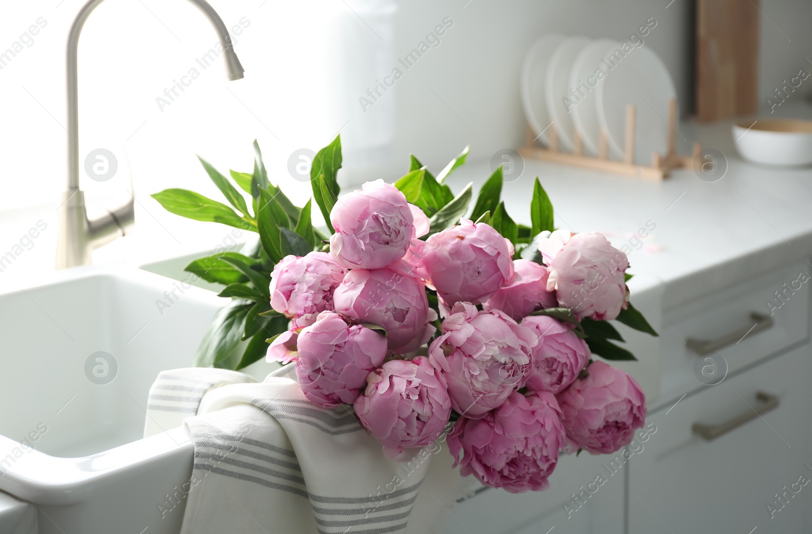 Photo of Bouquet of beautiful pink peonies in kitchen sink