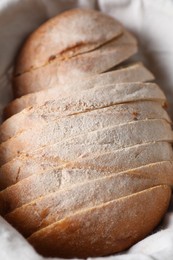 Photo of Slices of fresh bread on cloth in basket, top view