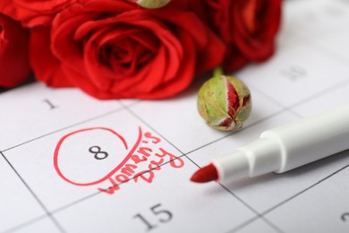 Roses and red marker on calendar near date 8th of March, closeup. International Women's Day