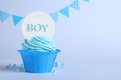 Beautifully decorated baby shower cupcake with cream and boy topper on light background. Space for text