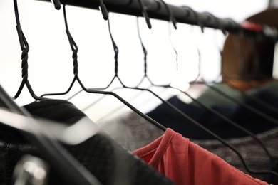 Photo of Different stylish clothes on rack indoors, closeup