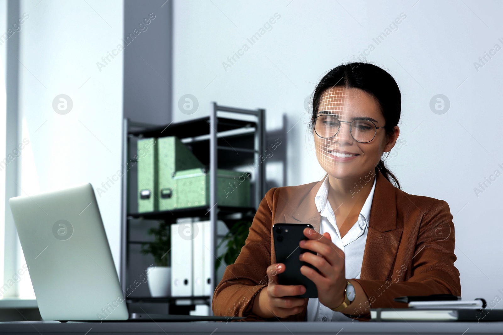 Image of Woman using smartphone with facial recognition system in office. Security application scanning her face for approving owner's identity