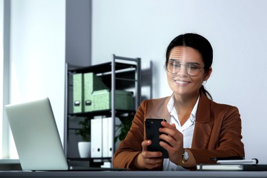 Image of Woman using smartphone with facial recognition system in office. Security application scanning her face for approving owner's identity
