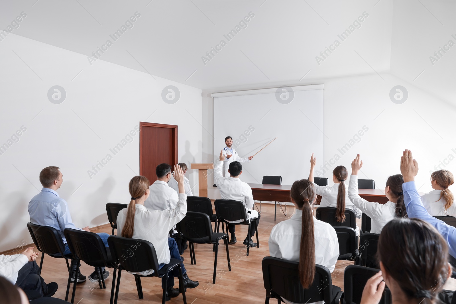 Photo of Doctor giving lecture in conference room with projection screen