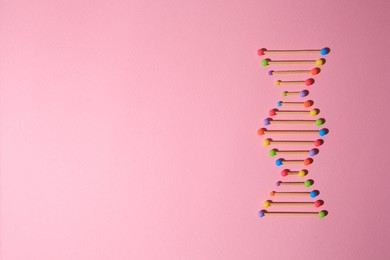 Photo of Model of DNA molecular chain on pink background, top view. Space for text