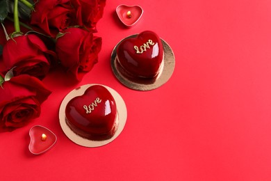 St. Valentine's Day. Delicious heart shaped cakes and roses on red background, flat lay. Space for text