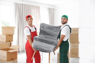 Photo of Male movers carrying armchair in new house