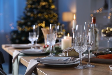 Photo of Christmas table setting with festive decor and dishware indoors