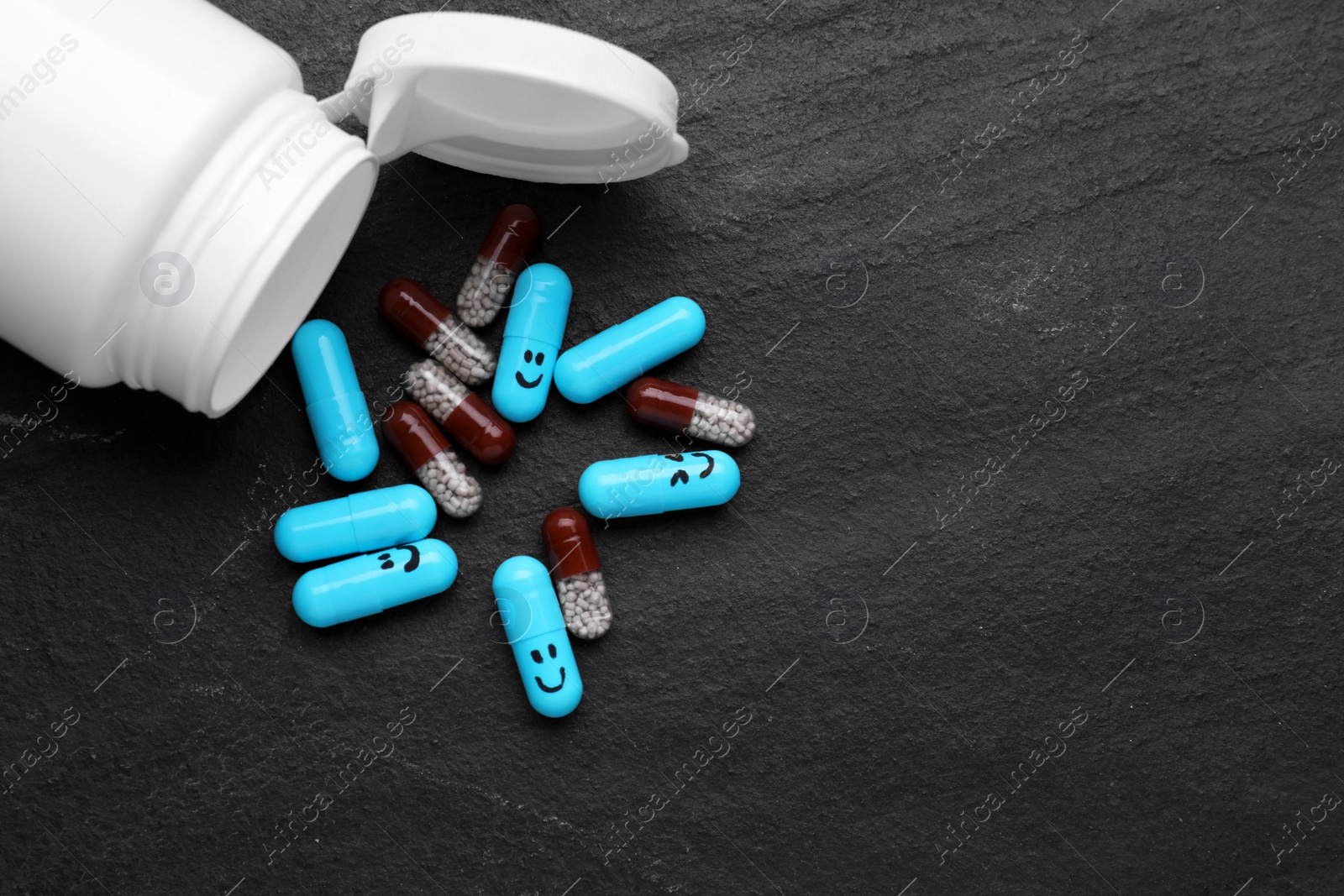 Photo of Antidepressants with happy emoticons and medical jar on black background, flat lay. Space for text