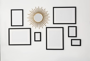 Empty frames and mirror hanging on white wall indoors