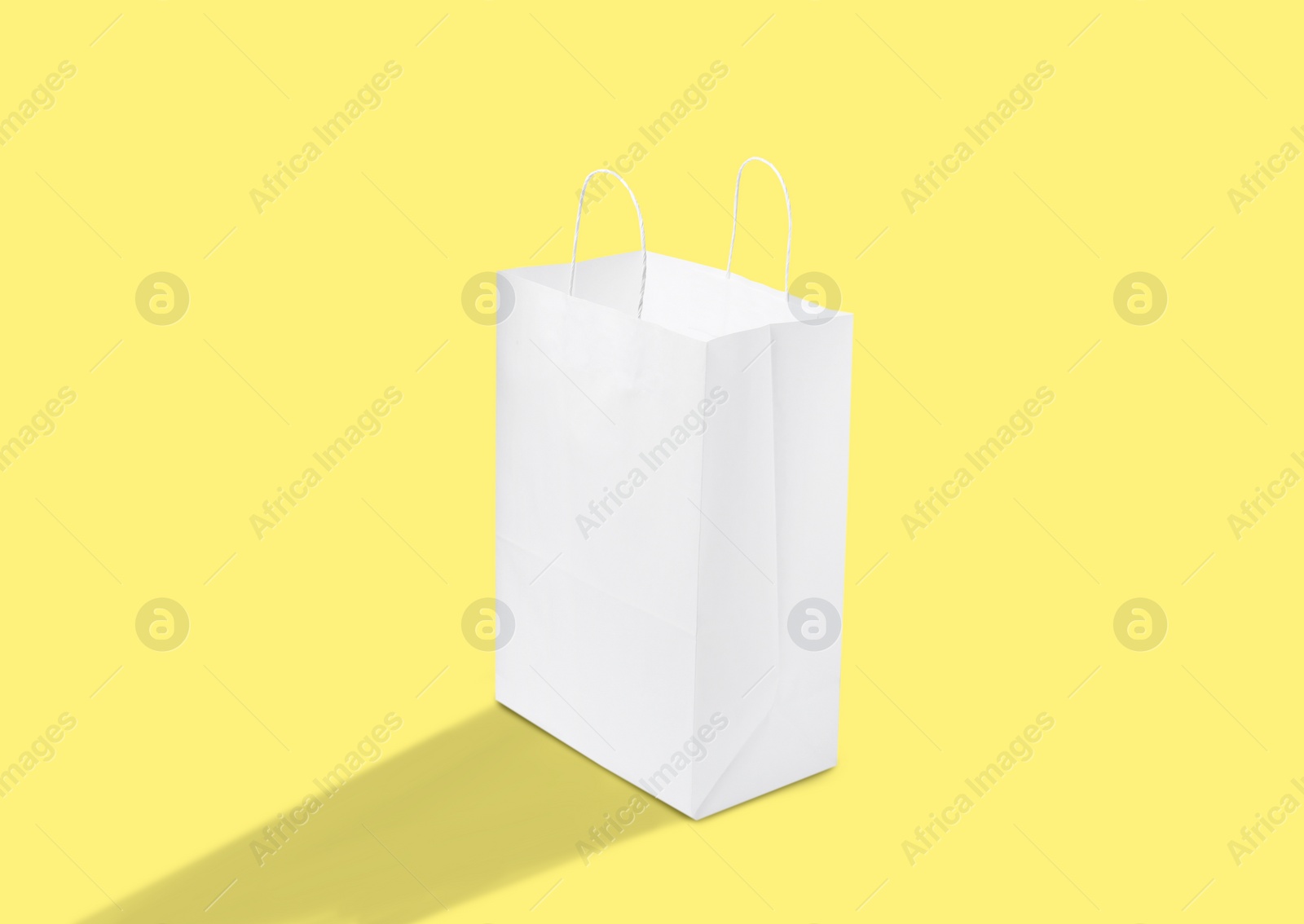 Image of White paper bag on yellow background. Mockup for design