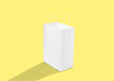 Image of White paper bag on yellow background. Mockup for design