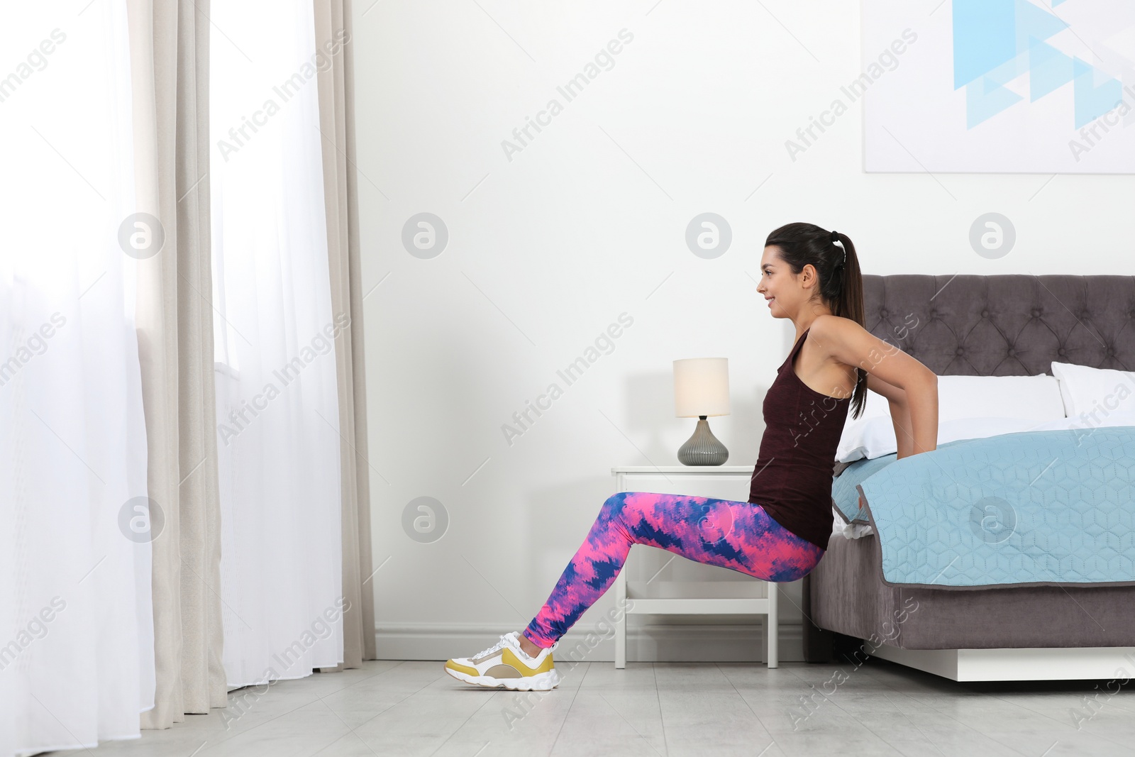 Photo of Young woman in fitness clothes doing exercise at home. Space for text