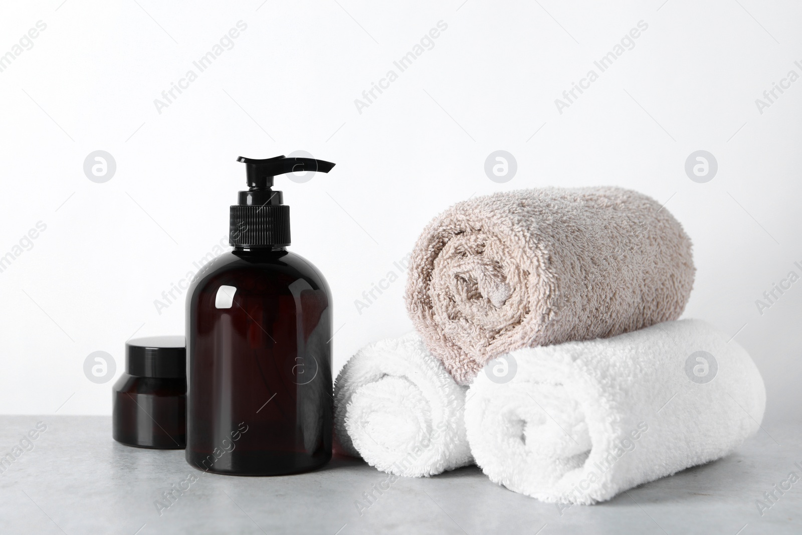 Photo of Cosmetic products and towels on light grey table