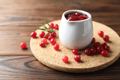 Photo of Cranberry sauce, fresh berries and rosemary on wooden table, space for text