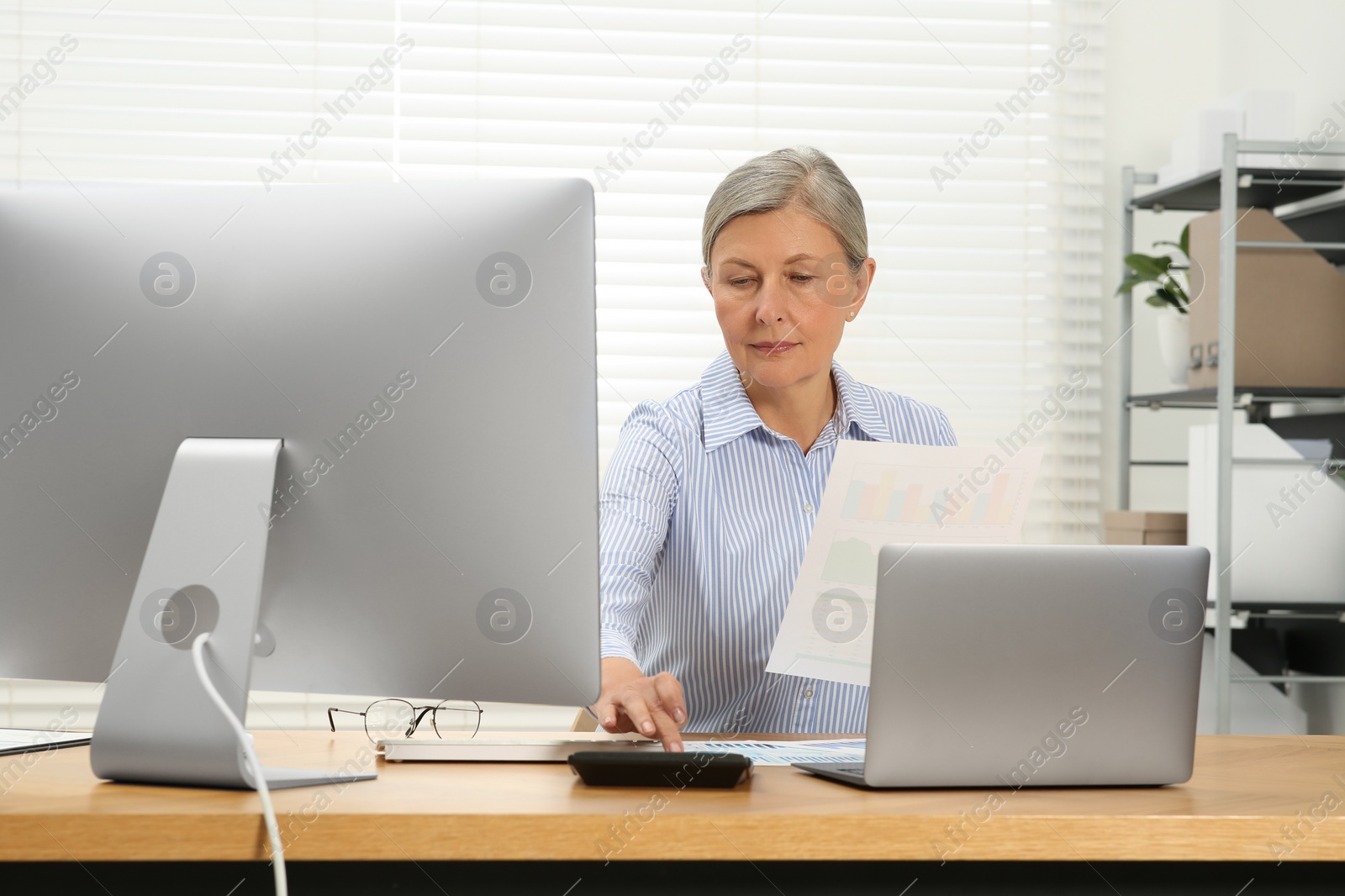 Photo of Senior accountant working at wooden desk in office