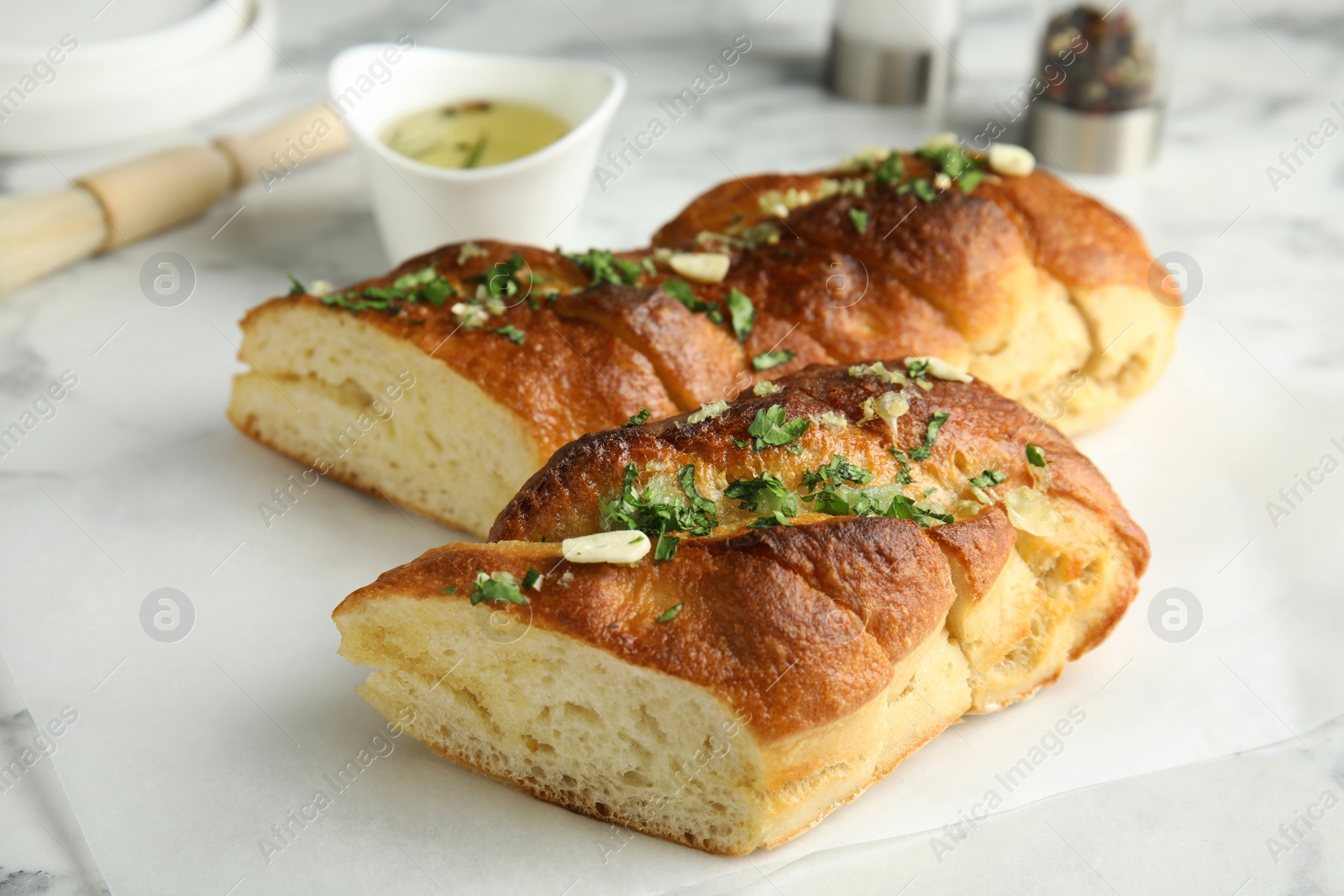 Photo of Delicious homemade garlic bread with herbs on table