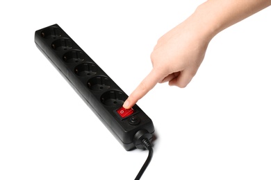 Woman pressing power button of extension cord on white background, closeup. Electrician's equipment