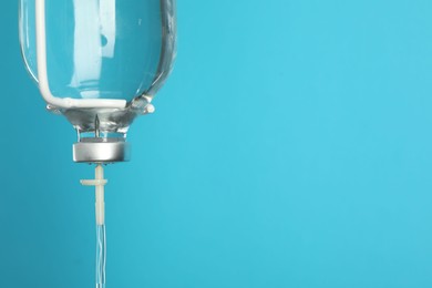 Photo of IV infusion set on light blue background, closeup. Space for text
