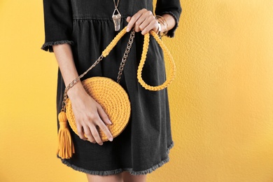 Young woman in stylish outfit with purse on color background, closeup