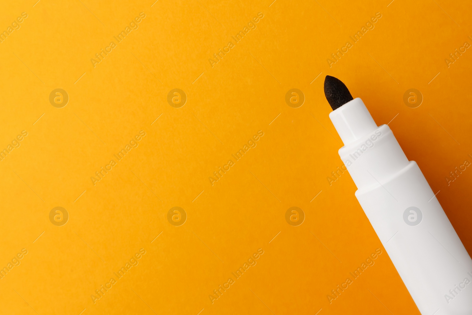 Photo of Black marker on orange background, top view. Space for text