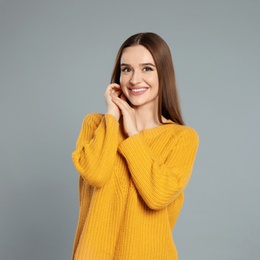 Beautiful young woman in yellow sweater on grey background. Winter season