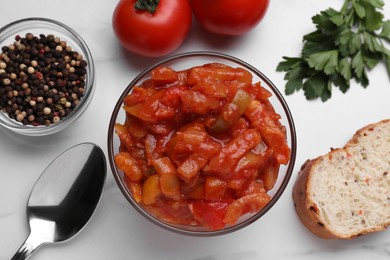 Photo of Delicious lecho in glass bowl and ingredients on white table, flat lay