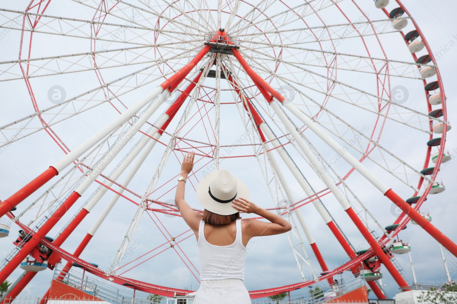 Photo of Young woman near Ferris wheel outdoors, low angle view