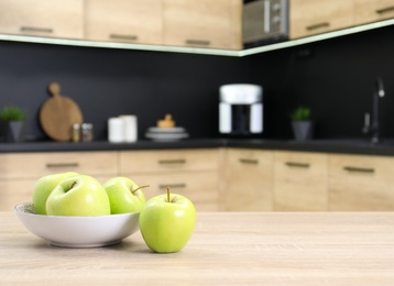 Fresh green apples on wooden table in kitchen. Space for text